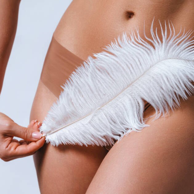 Soft white feather held against the body, illustrating gentle, discreet care