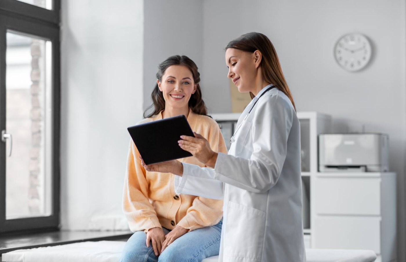 Doctor showing a tablet to a smiling patient in a bright consulting room